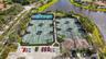 Community recreation area featuring multiple tennis courts, pickleball courts, and a clubhouse with a tile roof