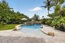 Freeform pool with a rock waterfall feature and integrated sun shelf
