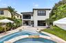 Expansive outdoor living area featuring a free-form pool with a stone coping, a paved patio, and established landscaping