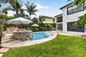 Resort-style backyard featuring a freeform swimming pool, integrated spa with stone surround, and a tiered rock waterfall