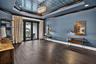 Hardwood-finish flooring complementing a tray ceiling with a blue textured inlay and chandelier