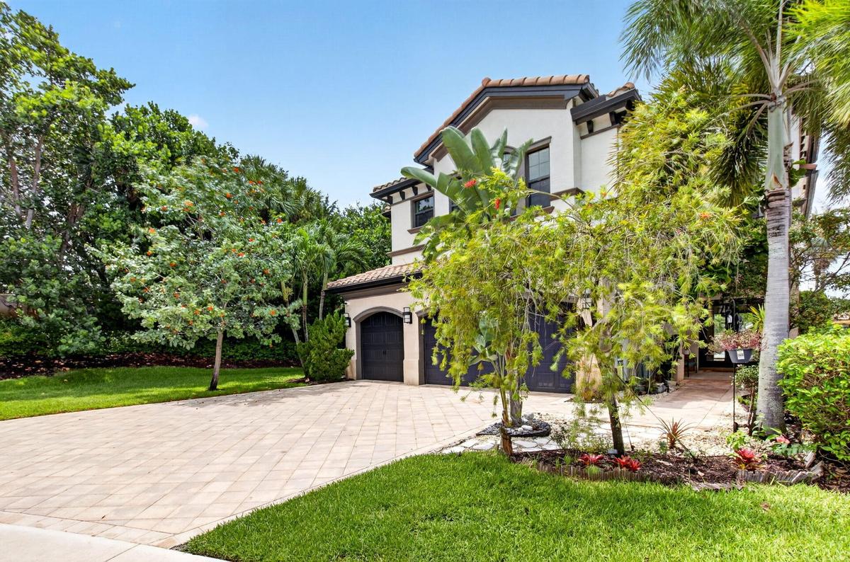 Mediterranean-style exterior featuring stucco finish, tile roof, and dark-toned garage doors