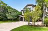 Mediterranean-style exterior featuring stucco finish, tile roof, and dark-toned garage doors