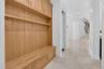 Built-in wood mudroom storage featuring a bench, shelving, and upper cabinetry