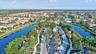Expansive neighborhood featuring a gated entrance, mature palm trees, manicured landscaping, and multiple waterfront properties
