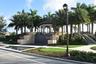 Lush landscaping featuring mature palm trees and a decorative fountain with a tiered stone base