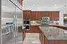 Gourmet kitchen featuring a stainless steel side-by-side refrigerator, double wall ovens, a gas range with a contemporary hood, wood cabinetry, and st