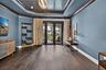 Spacious room featuring dark wood-finish flooring, blue walls, and a decorative ceiling with a central chandelier
