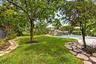 Expansive backyard featuring a lush lawn, mature trees, and natural stone pathways