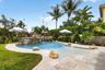 Curved swimming pool featuring a rock waterfall, sun shelf, and paver decking
