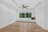 Light wood-finish flooring with white baseboards and window trim