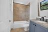 Bathroom featuring a tub/shower combination with tile surround and decorative accent band, a single vanity with granite countertop and undermount sink