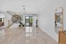 Spacious interior featuring large format tile flooring, a contemporary staircase with wood handrails, and an elegant multi-arm ceiling fixture