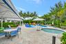Expansive outdoor amenity space featuring a hot tub, a dedicated splash pad with water features, multiple shaded cabanas, and a surrounding patio with