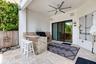 Covered outdoor patio featuring a built-in outdoor kitchen with stone-finish countertops, a ceiling fan, and sliding glass doors