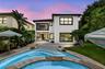 Backyard oasis featuring a freeform swimming pool, expansive paved patio, and a built-in outdoor kitchen