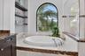Soaking tub with chrome fixtures, set against an arched window with grid panes