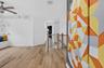 Open interior featuring wood-finish flooring, a built-in window bench, white floating shelves, and a ceiling fan