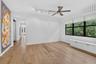 Spacious room featuring wood-finish flooring, white walls, and a large window with black framing