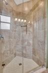 Glass-enclosed shower featuring large format wall tiles, a decorative mosaic accent band, a built-in shower niche, and a corner window