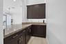 Custom built-in cabinetry with gold-tone hardware, a light-toned patterned countertop, and an undermount sink with a gold-tone faucet