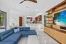 Open-concept living space with light-toned tile flooring, recessed lighting, a ceiling fan, and a built-in media center with shelving and lower cabine