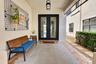 Covered front entry featuring double glass-paneled doors, a flush-mount exterior light fixture, and a patterned outdoor rug
