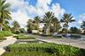 Entryway featuring paver roads, lush landscaping, multiple water features, and mature palm trees