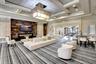 Spacious room featuring a multi-level coffered ceiling, large rectangular chandelier, and striped floor covering