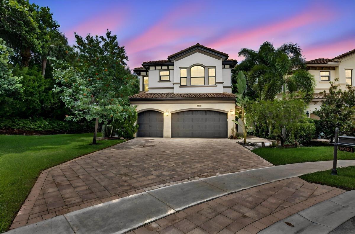 Two-story residence featuring a tile roof, arched entryway, and a two-car garage
