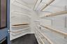 Custom closet system featuring white wire shelving with wood-finish accents, integrated wire baskets, and dark wood-finish flooring