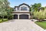 Stucco exterior featuring a tile roof, arched garage doors, and a paver driveway