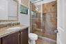 Bathroom featuring a walk-in shower with full-height tile surround and glass enclosure, a built-in shower niche, and a dual-function shower head