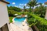 Resort-style pool area featuring a freeform swimming pool with integrated spa, rock waterfall, and surrounding stone deck