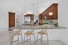 Kitchen featuring an expansive island with a light-toned countertop, warm wood-finish cabinetry, stainless steel appliances, and under-cabinet lightin
