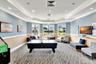 Spacious common area featuring patterned carpeting, tray ceilings with recessed lighting, and a bay window configuration