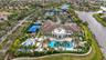 Extensive community amenities featuring multiple swimming pools, a central clubhouse building, tennis courts, and surrounding waterways