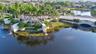 Gated community entrance featuring a bridge over a pond, water features, and extensive palm tree landscaping
