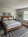Bedroom with dark wood finished floors and a baseboard heating unit