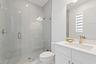 Bathroom with glass shower, white vanity, and marble tile