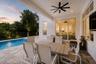 Covered outdoor patio with dining table, chairs, ceiling fans, and pool view