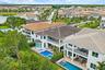 Aerial view of the home showing pool, roof, and surrounding neighborhood