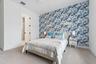 Bedroom with blue floral accent wall, white nightstands, and carpet flooring
