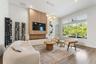 Living room with wine storage shelving, mounted TV, and large windows with garden view