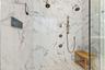 Marble shower with multiple showerheads and built-in bench