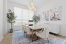 Dining room with wood table, upholstered chairs, artwork, and area rug