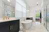 Bathroom with dark cabinetry, dual vanity, freestanding tub, and marble tile