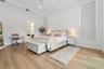 Bedroom with white bed, desk area, and wood flooring