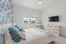 Bedroom with blue floral accent wallpaper, mounted TV, and dresser