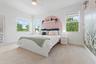 Bedroom with arched accent wall and windows overlooking trees